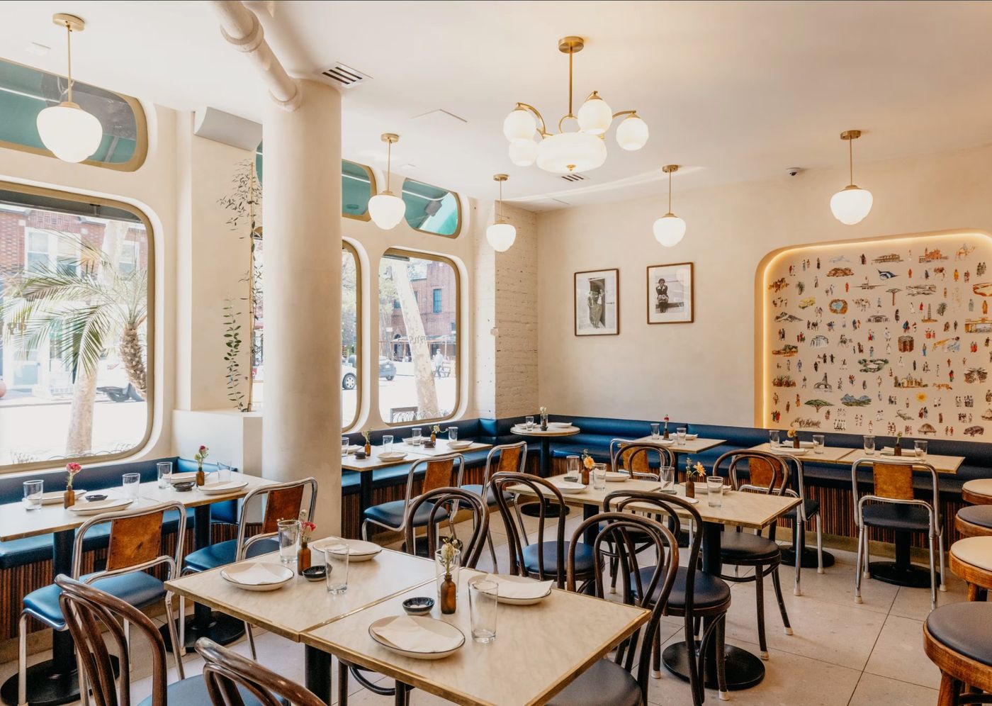 Sunlit Makina dining room with arched windows, bentwood chairs, and an illustrated Habesha mural