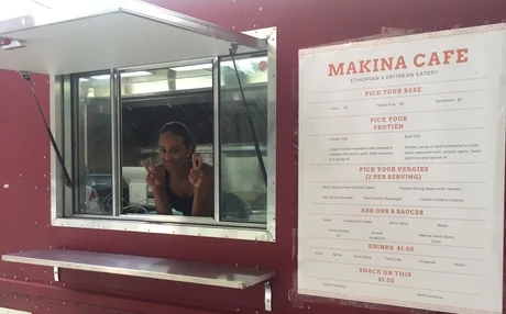The first Makina Cafe food truck in 2017, painted red: peace signs from the open serving window, with the Makina Cafe menu board beside it