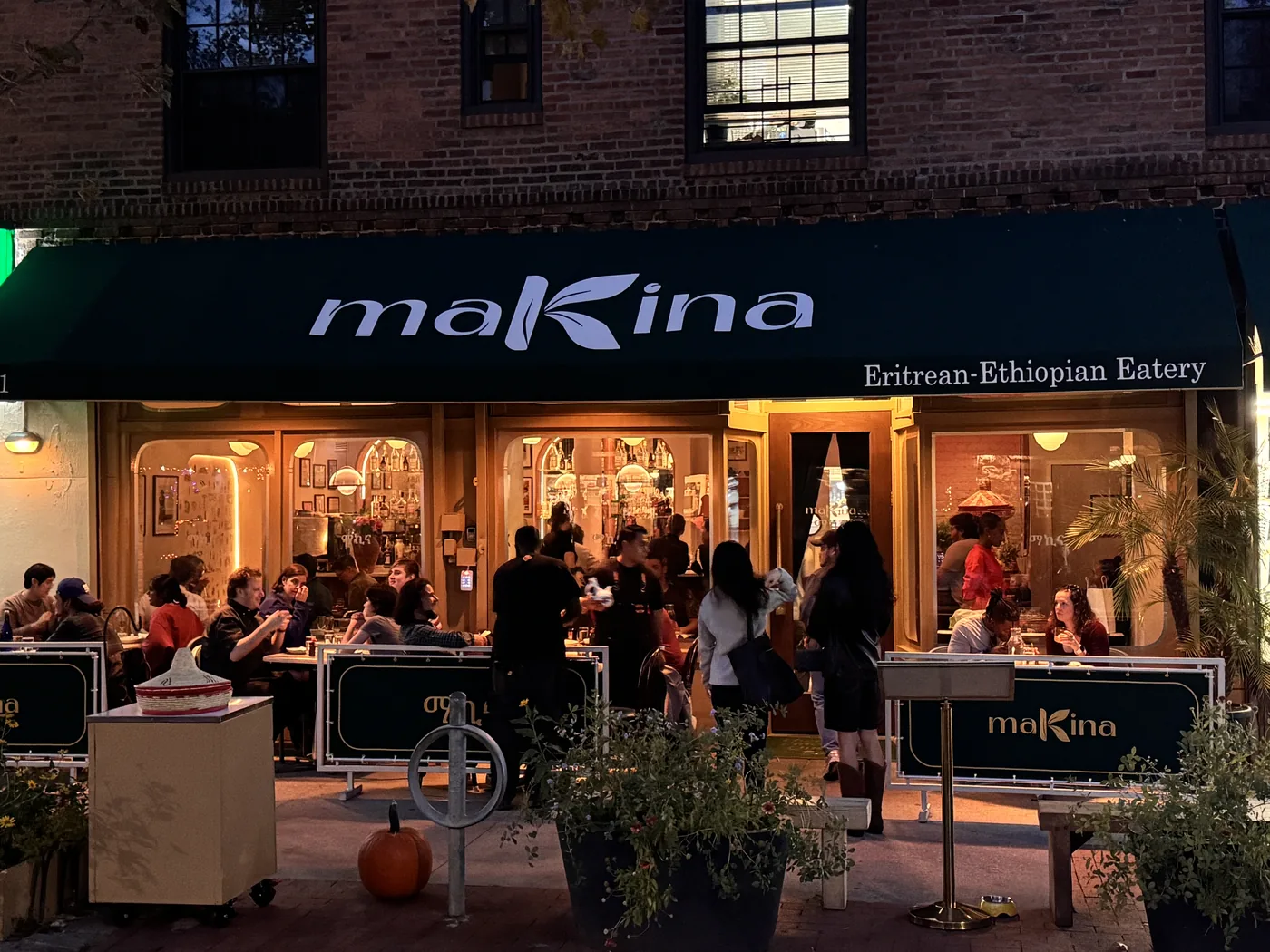 Makina's patio on a busy evening in Sunnyside, the glowing Makina awning over tables full of diners