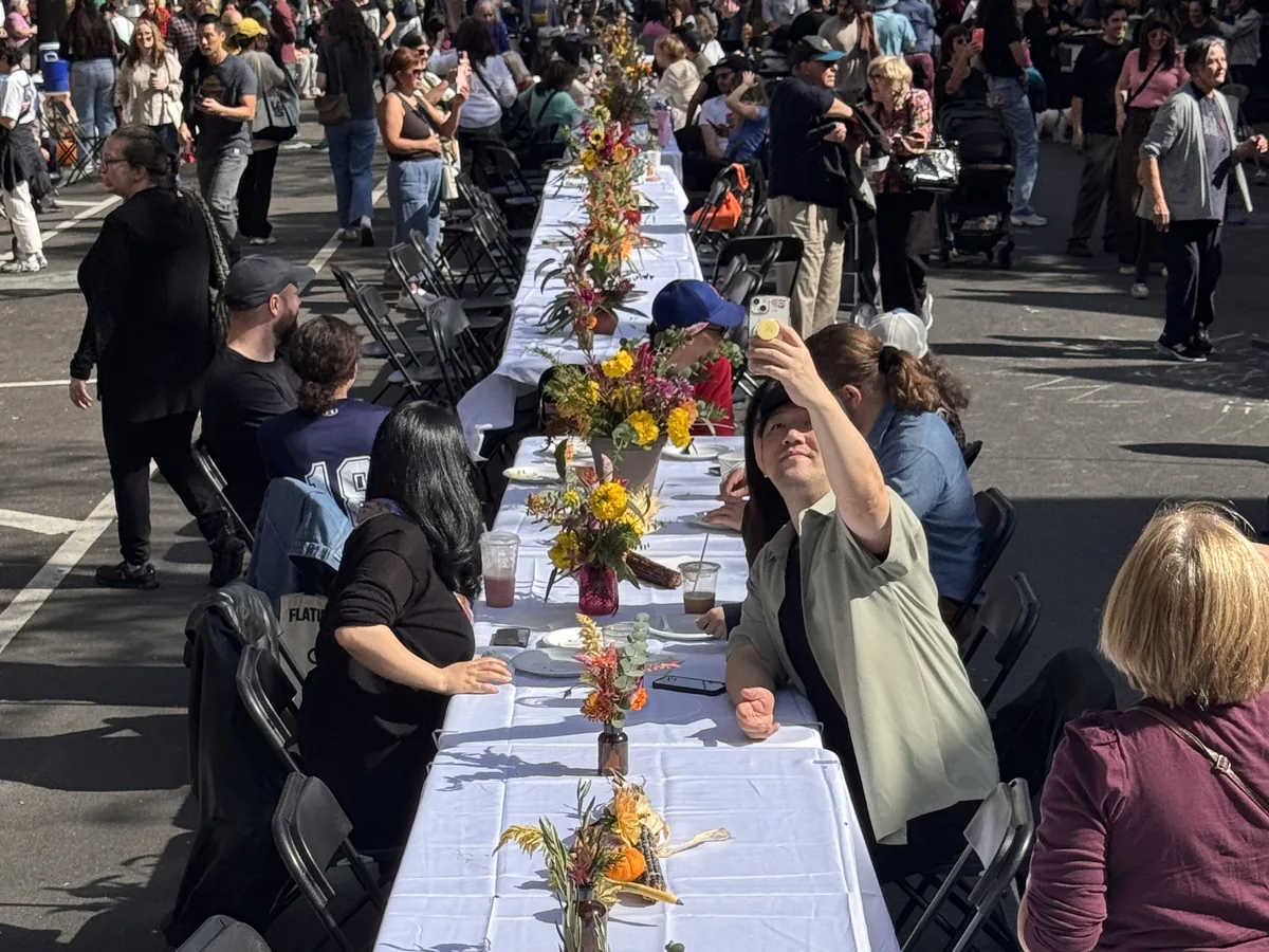 A Makina long-table feast down a Sunnyside street: white cloths, autumn flowers and guests seated along both sides